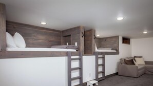 A room with bunk beds, a small bench, and a sofa.