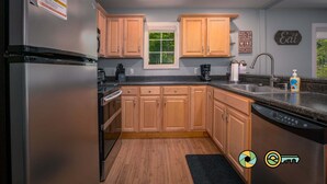 A modern kitchen with wooden cabinets, a stainless steel refrigerator, a window, and a sink.