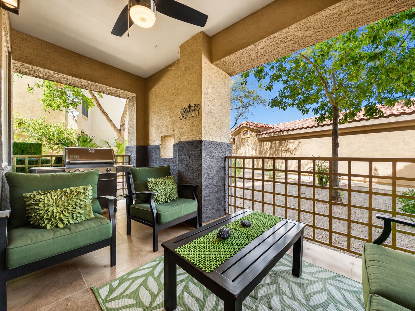 Un espace patio aménagé avec du mobilier d’extérieur, un ventilateur de plafond et une vue sur la rue.
