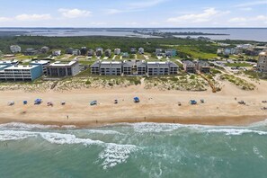 Un hotel a la costa amb diverses dependències, una platja de sorra i vistes a l'oceà.