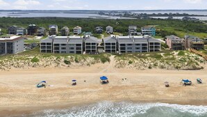 Ein Hotel direkt am Strand mit mehreren Gebäuden, einem Sandstrand und Wellen.