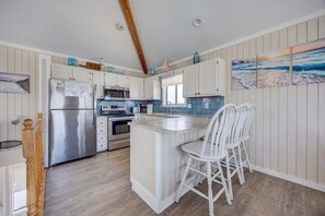 A kitchen with a central island, white cabinetry, a stainless steel refrigerator, and a microwave. - 1725 - Sunshine and Whiskey 4BR oceanside retreat with private pool, hot tub, and deck access. (Corolla)