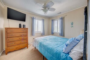 A bedroom with a bed, a dresser, a ceiling fan, and a TV mounted on the wall. - 1725 - Sunshine and Whiskey 4BR oceanside retreat with private pool, hot tub, and deck access. (Corolla)