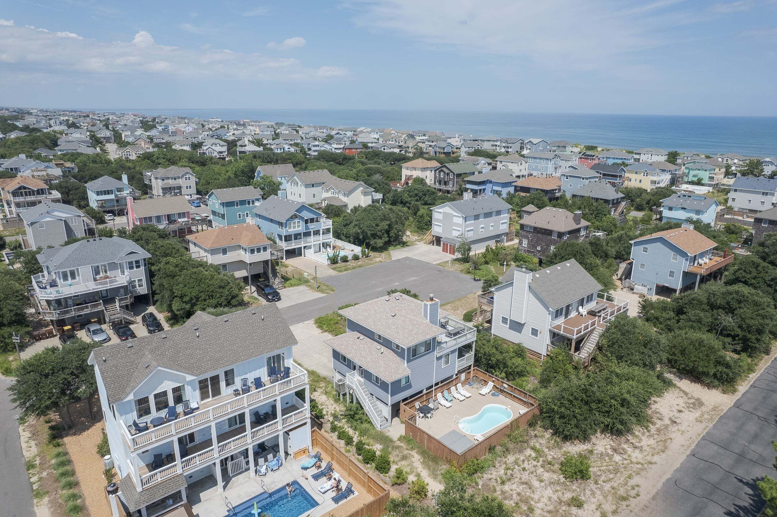 A residential area with houses, a swimming pool, and a view of the ocean.