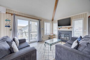 Ein Wohnzimmer mit Kamin, einem an der Wand befestigten Fernseher und einem Balkon mit Blick.