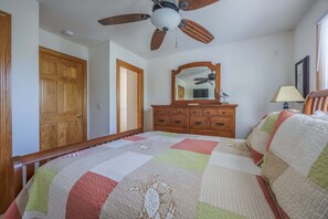 A bedroom with a wooden bed, a ceiling fan, a dresser, and a mirror. - 1925 - Lemon Cooler Your Corolla dream stay: 6BR, pool, hot tub, theater room & sunny decks. (Corolla)