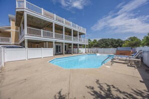 Un edificio de dos pisos con piscina, zona de estar al aire libre y patio cubierto.
