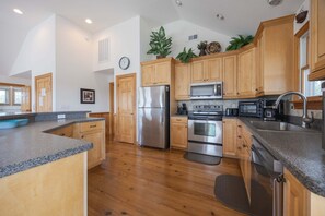 A modern kitchen with wooden cabinets, stainless steel appliances, and a granite countertop. - 1925 - Lemon Cooler Your Corolla dream stay: 6BR, pool, hot tub, theater room & sunny decks. (Corolla)