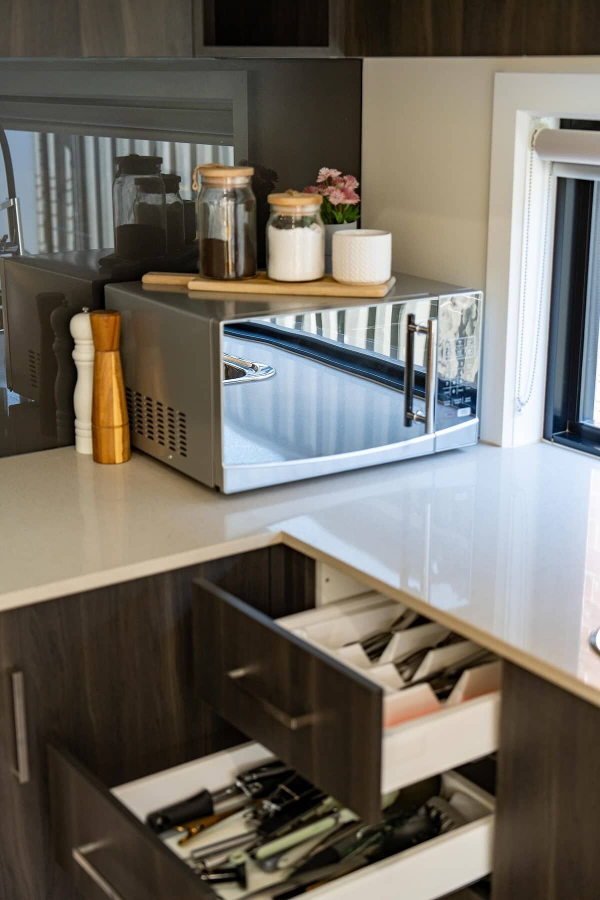 A kitchen with a stainless steel appliance, wooden utensils, and a window.
