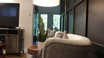 A living room with a television, a sofa, a lamp, and a potted plant.