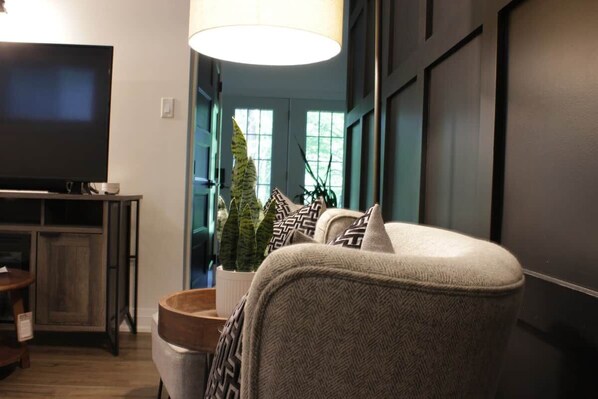 A living room with a television, a sofa, a lamp, and a potted plant.