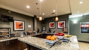 A breakfast bar with a coffee machine, fruit bowl, and a Coca-Cola dispenser.