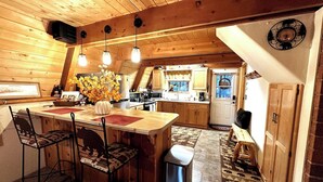A wooden interior with a kitchen, dining area, and a clock on the wall.