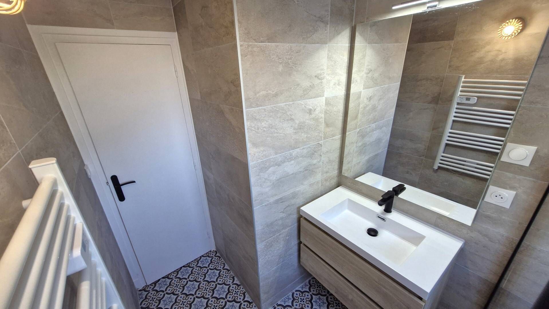 A modern bathroom with a white sink, a mirror, and a towel rack.