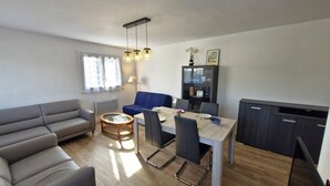 Ein modernes Wohnzimmer mit einer Couch, einem Esstisch, Stühlen und einem Schrank.