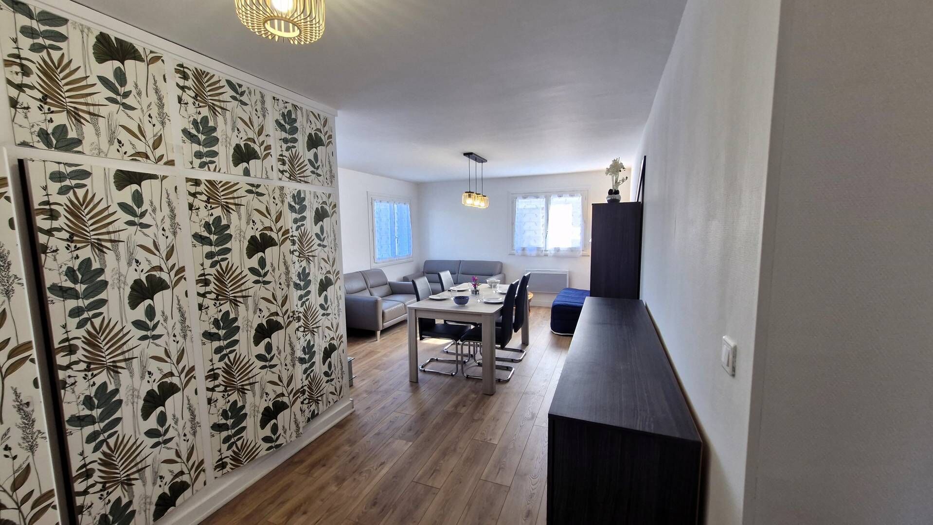 A modern living room with a dining area, a sofa, a coffee table, and a TV stand.