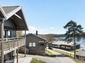 Uma cabana com varanda, alpendre coberto e vista para um lago.