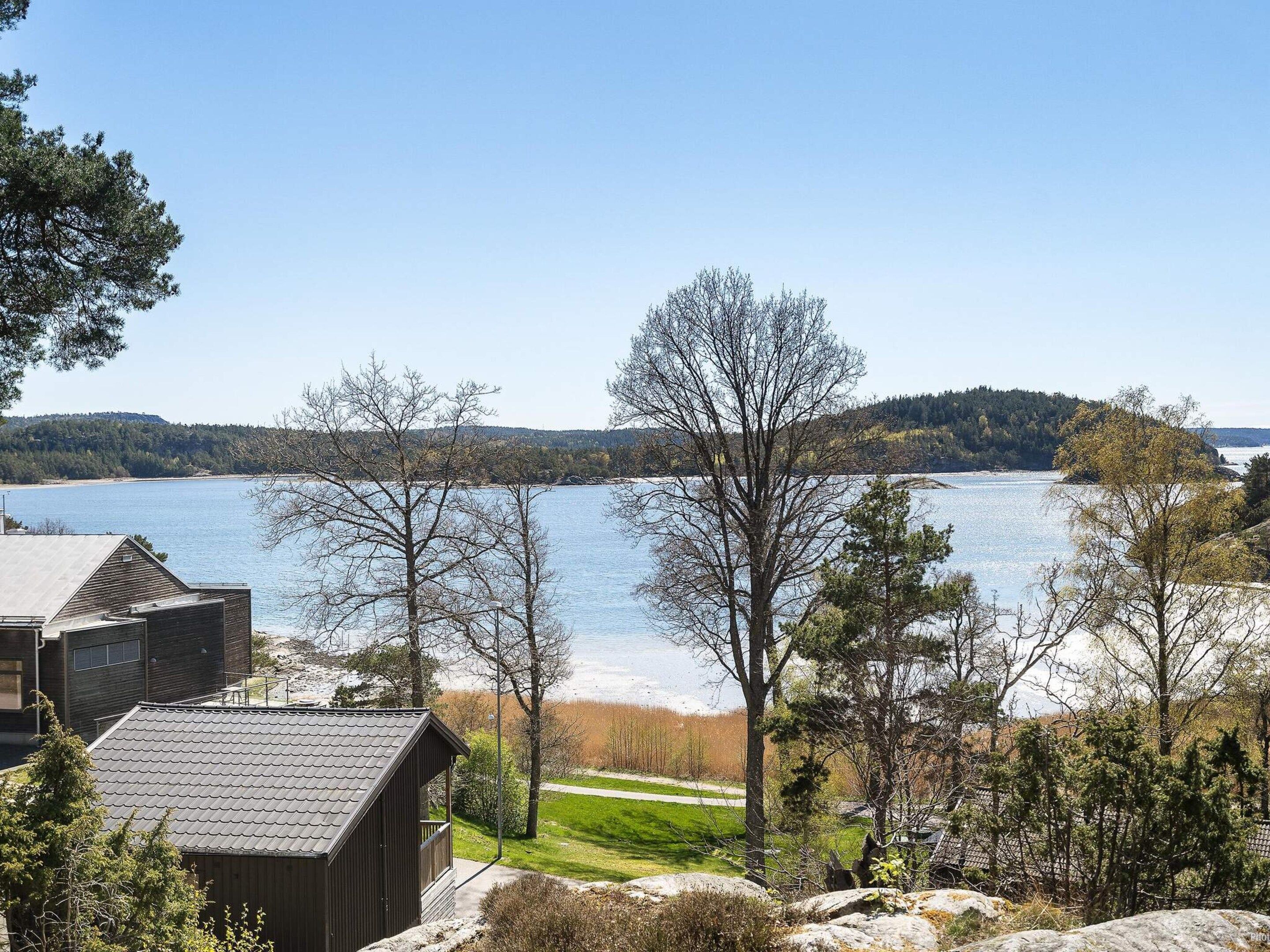 A lakeside property with a cabin, a view of the lake, and a forested hill in the background.