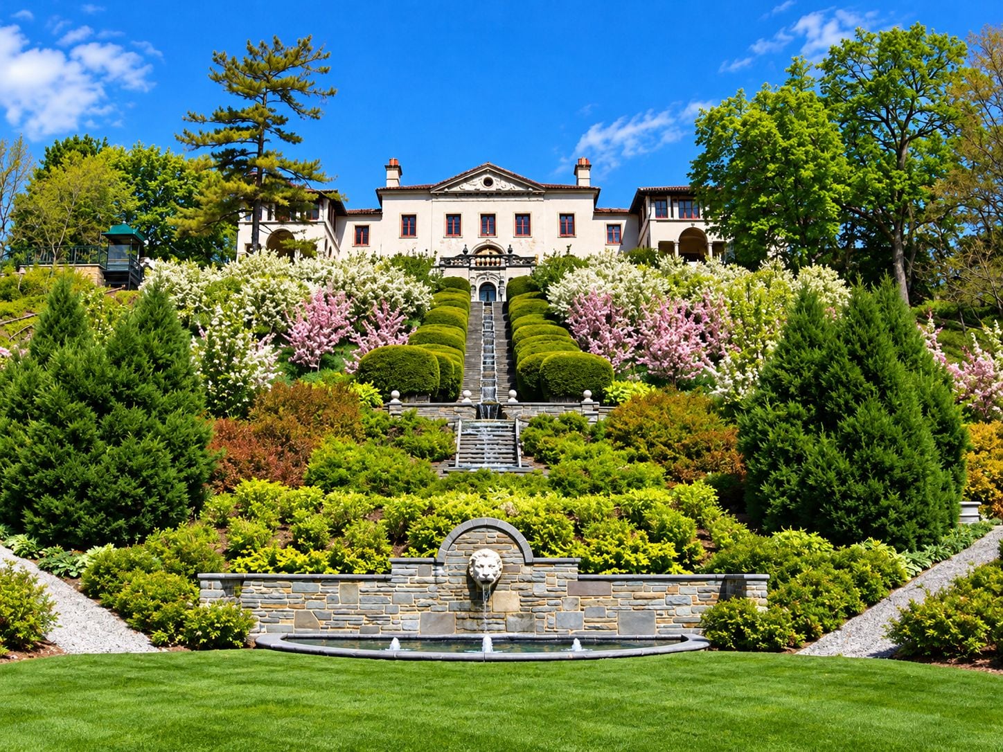 Un edificio grande y señorial con un jardín formal, que incluye una fuente y setos bien cuidados.