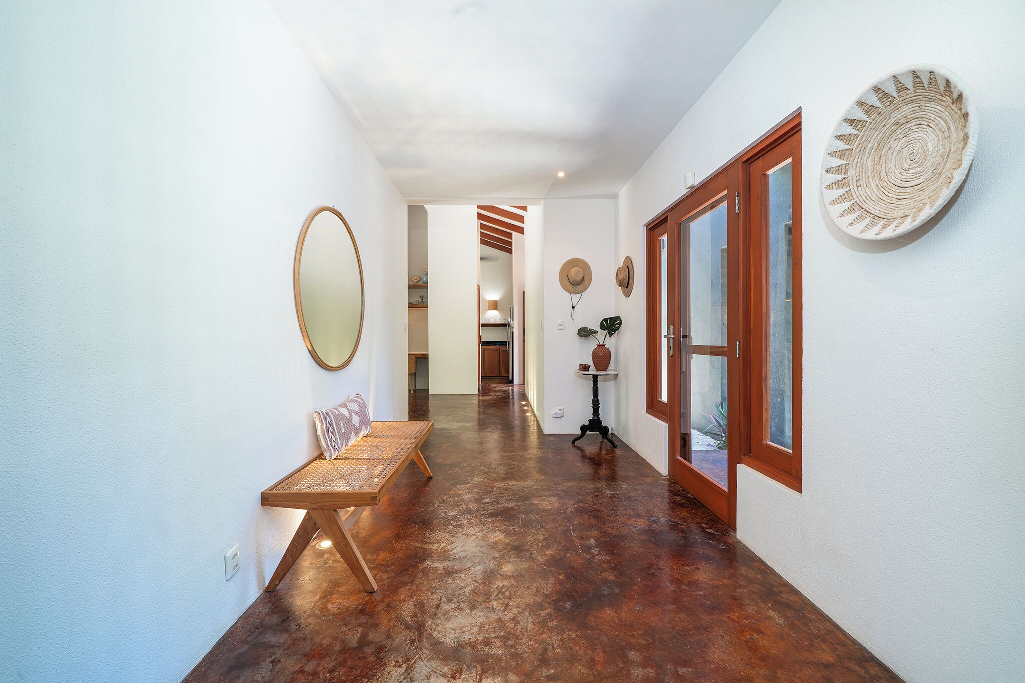 A hallway with a bench, a mirror, a door, and a wall-mounted decorative plate.