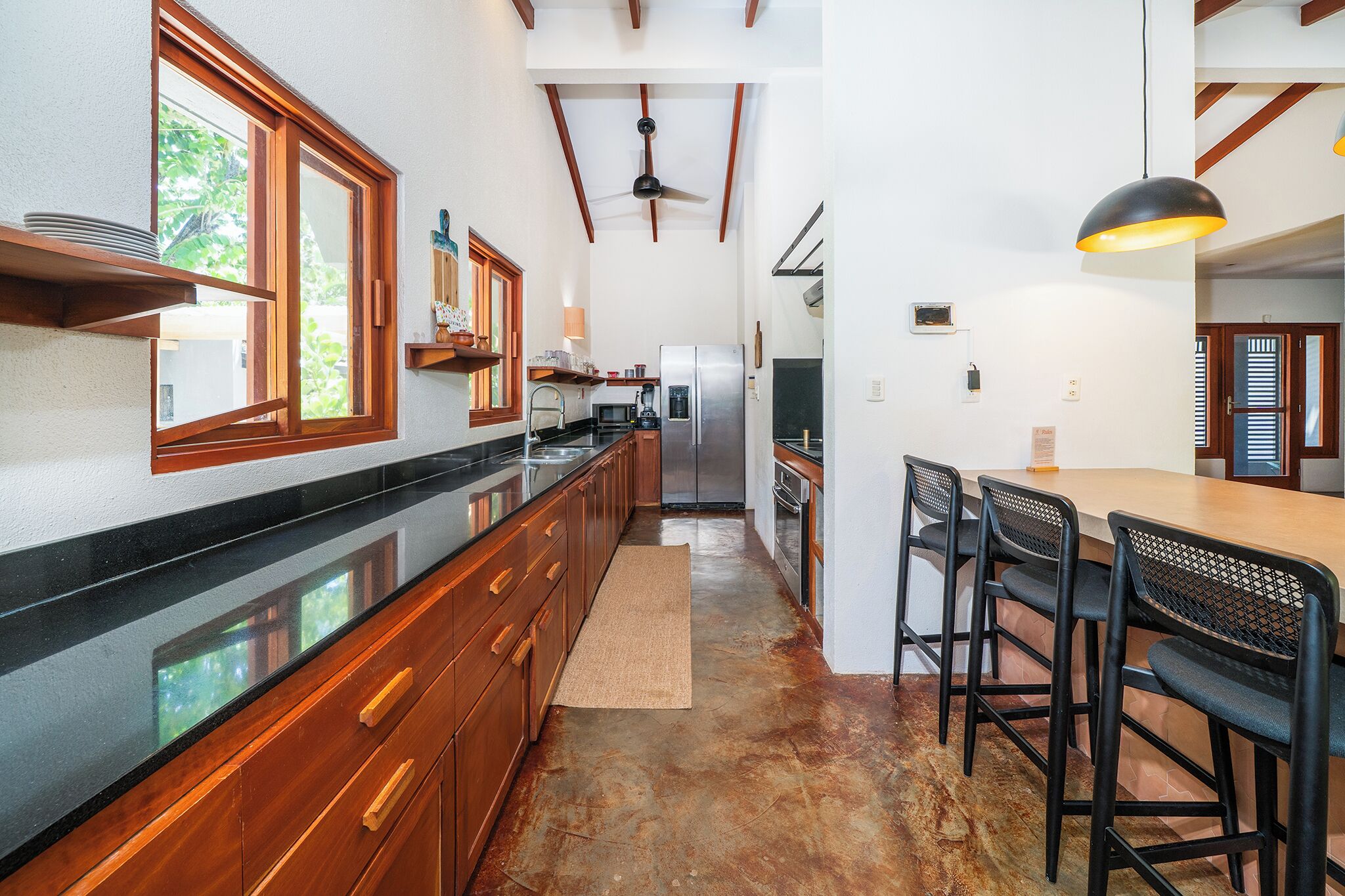 A kitchen with wooden cabinets, a stainless steel refrigerator, and a dining area with a table and chairs.