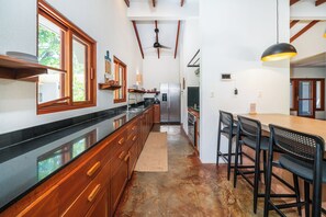 Una cocina con armarios de madera, un refrigerador de acero inoxidable y una zona de comedor con una mesa y sillas.
