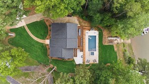 Luchtbeeld van een huis met een zwembad, omringd door een verzorgd gazon en bomen.
