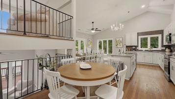 A spacious kitchen with white cabinetry, a dining area with a round table and chairs, and a balcony with a view.