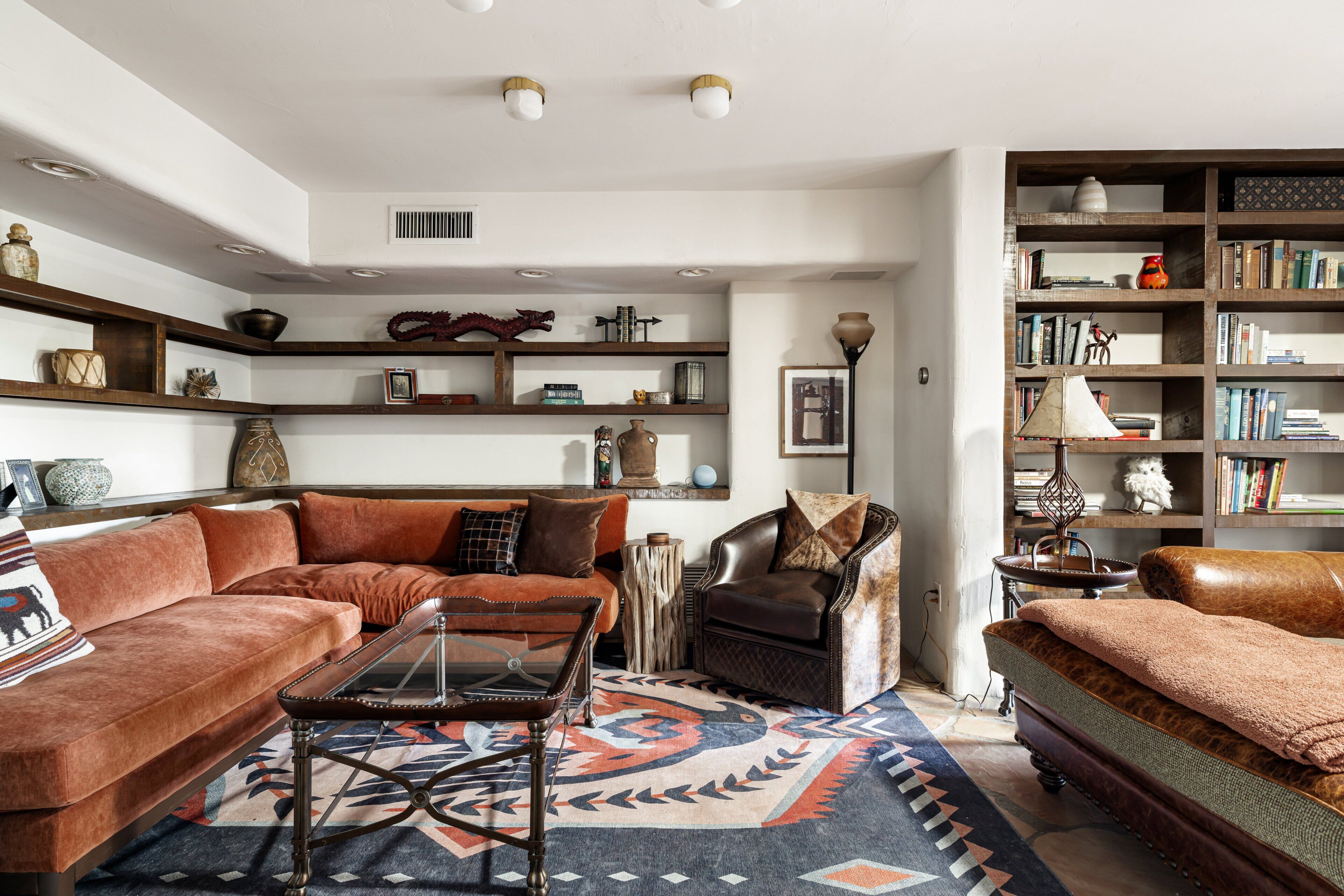 A living room with a sofa, armchair, coffee table, and bookshelf.