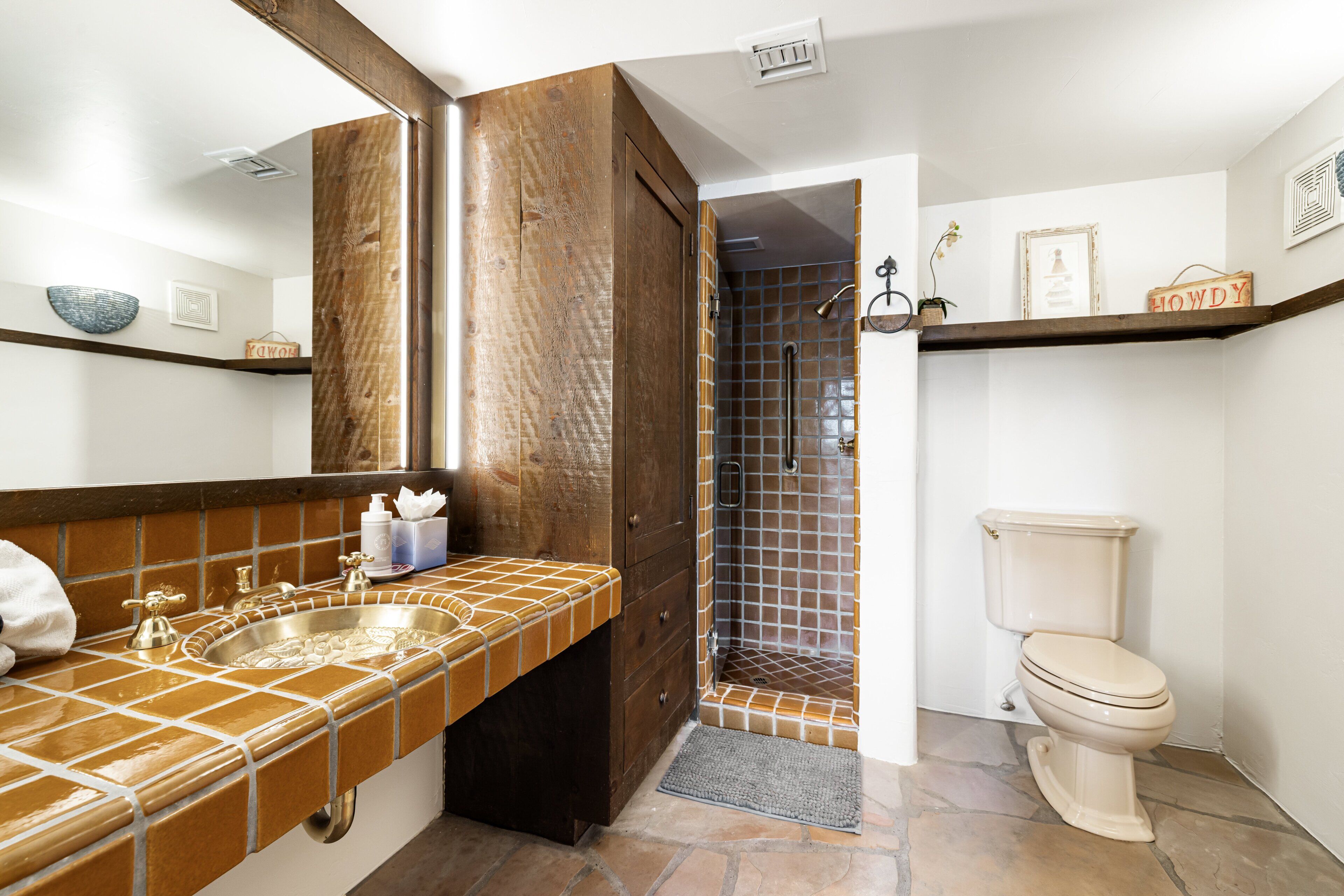 A bathroom with a tiled sink, a toilet, and a shower area.