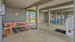 Ulkona oleva katettu alue, jossa on betonipilarit, piknikpöytä ja viemäräritilä.