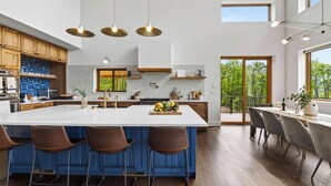 A modern kitchen with a large island, bar stools, pendant lighting, and a view of the outdoors. - Bates Ridge by Avantstay Secluded Catskills Retreat Near Hunter Mountain + Game Room (Haines Falls)