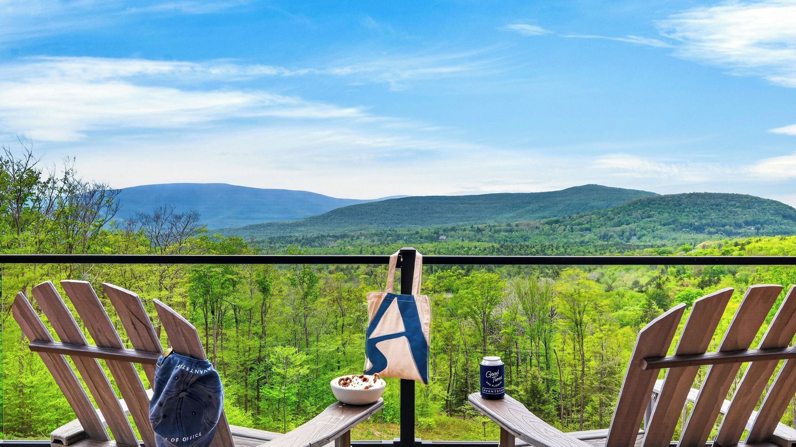 A balcony with two Adirondack chairs, a bottle, a bowl of cereal, and a can of beer.