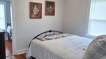 Un dormitorio con una cama, un ventilador de techo y dos cuadros en la pared.