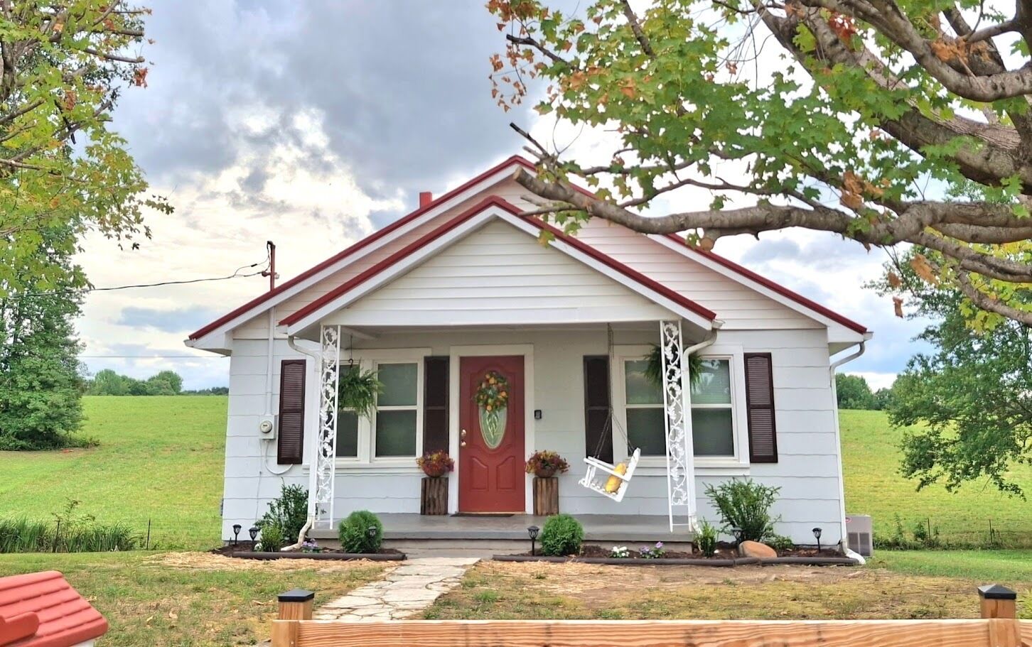 A single-story house with a red door, white siding, and a red roof.