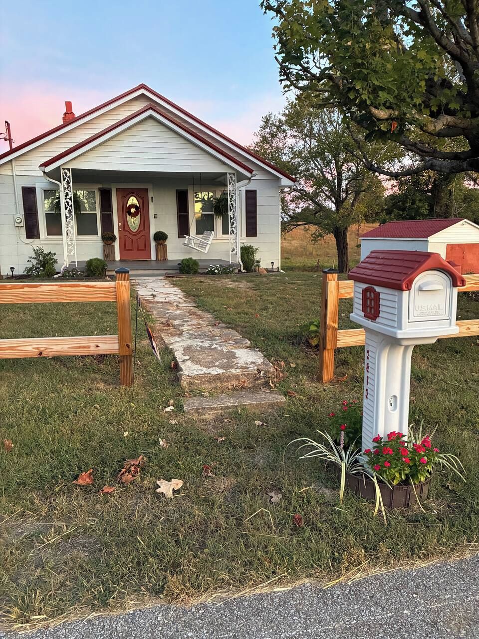 A house with a front porch, a mailbox, and a wooden fence.