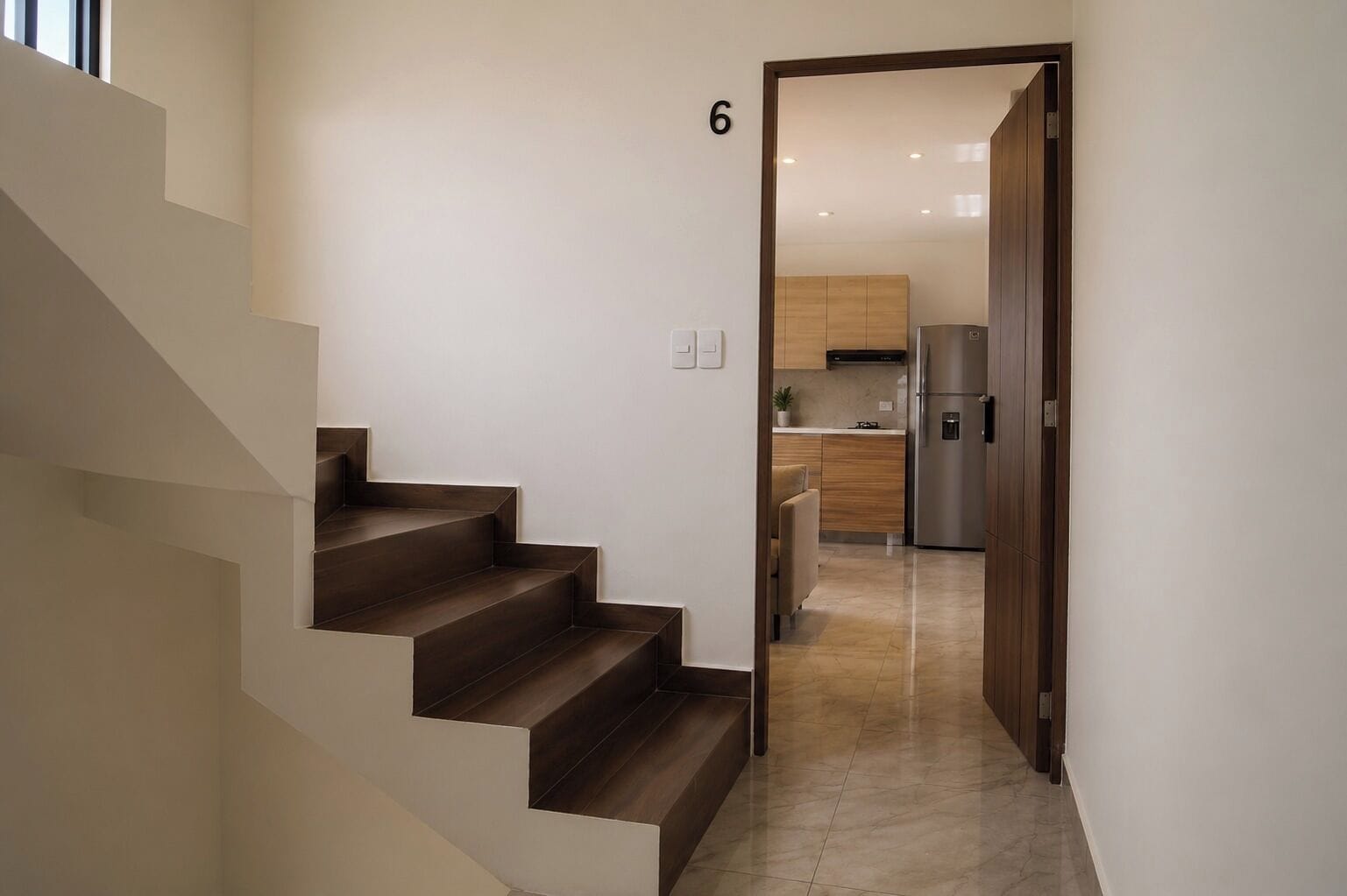 Un intérieur moderne comprenant un escalier, un coin cuisine et une porte portant le numéro 6.