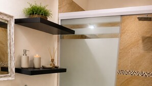 Un bagno con un lavandino bianco grande, un water, box doccia in vetro e un ripiano con articoli da toilette.