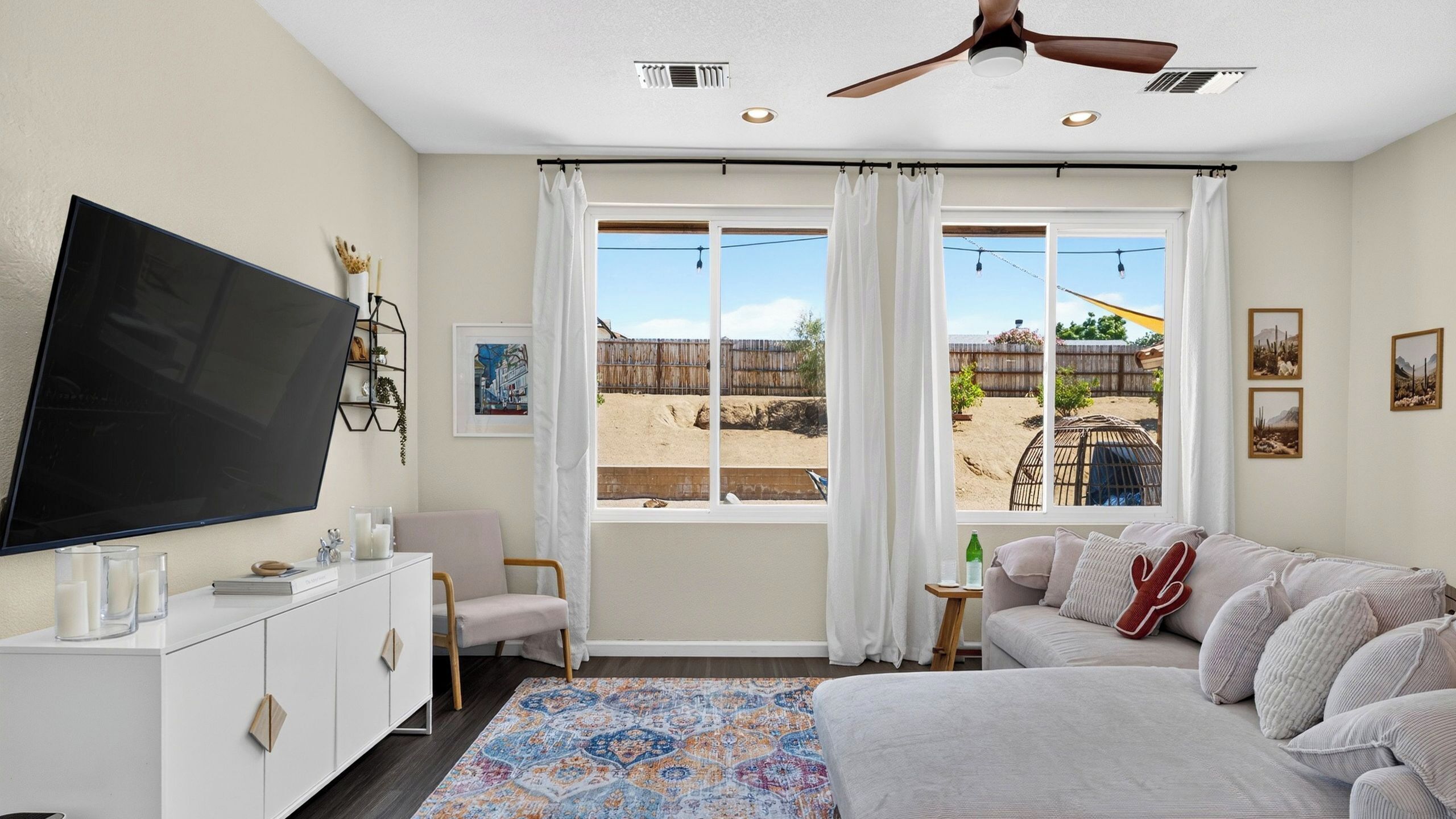 A bedroom with a bed, a TV, a desk, and a window with curtains.