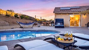 A backyard with a swimming pool, lounge chairs, a hammock, and a barbecue area. - The Light of the Desert by Avantstay Pool + Firepit + BBQ Mins to National Park + DT Yucca Valley (Yucca Valley)