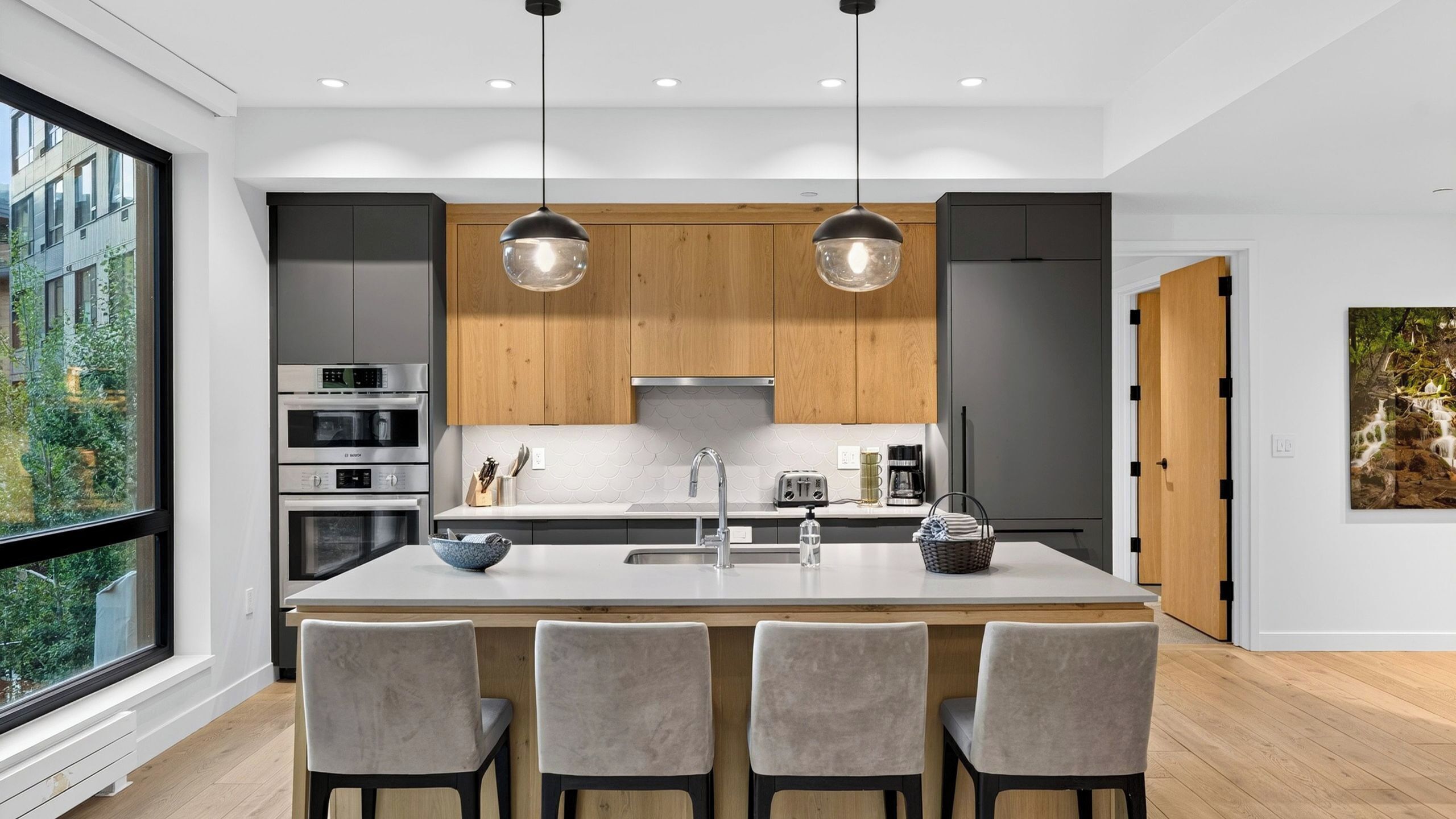 A modern kitchen with a central island, built-in appliances, and pendant lighting.