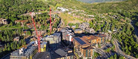 A mountainous town with modern buildings, roads, and a prominent red crane.