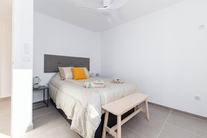 A bedroom with a bed, bedside table, lamp, and a ceiling fan.