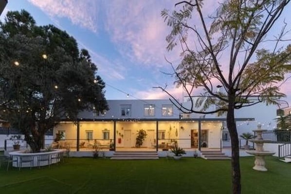 A modern house with a well-maintained lawn, a large tree, and a fountain.