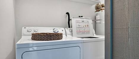 A laundry area with a washing machine, a dryer, and a wicker basket on the machine.