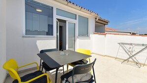Un patio al aire libre con una mesa, sillas, una ventana y un tendedero.