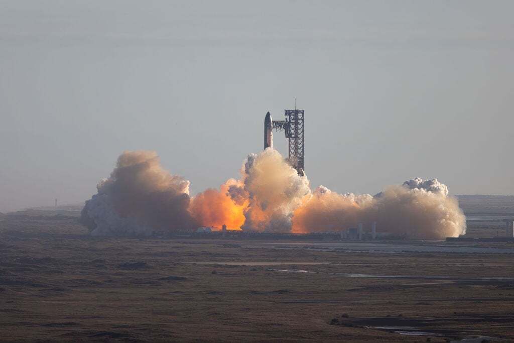 A rocket launch with a launch tower and smoke.