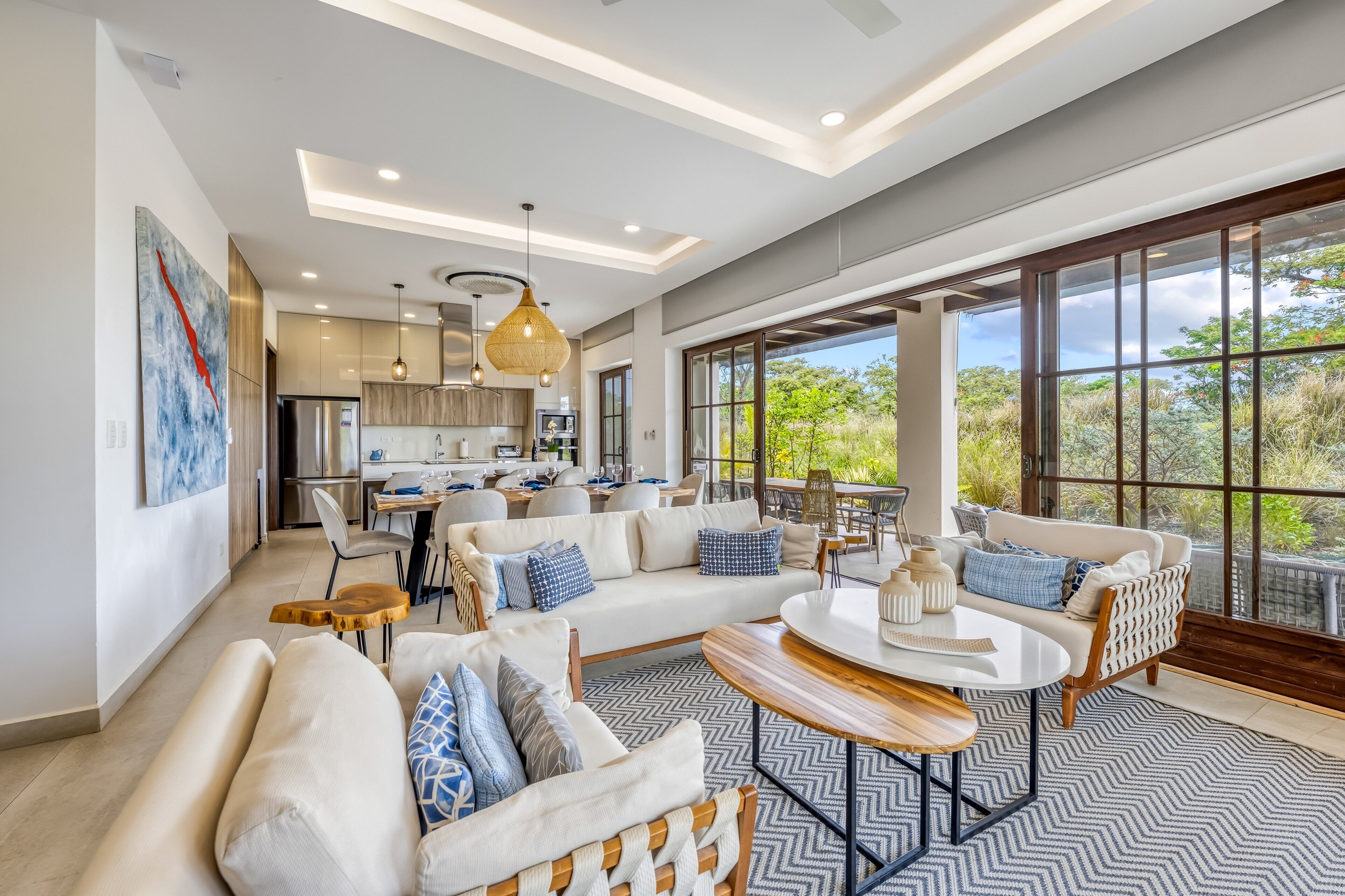 A spacious living area with a large sofa, a coffee table, and a view of the kitchen and outdoor patio.