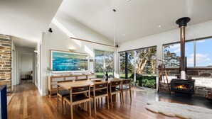 Ein stilvoller Essbereich mit Holztisch und Stühlen, einem großen Gemälde und einer Steinwand.
