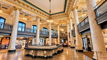 Un hall espacioso con columnas de mármol, una fuente central y un entresuelo con balcones.